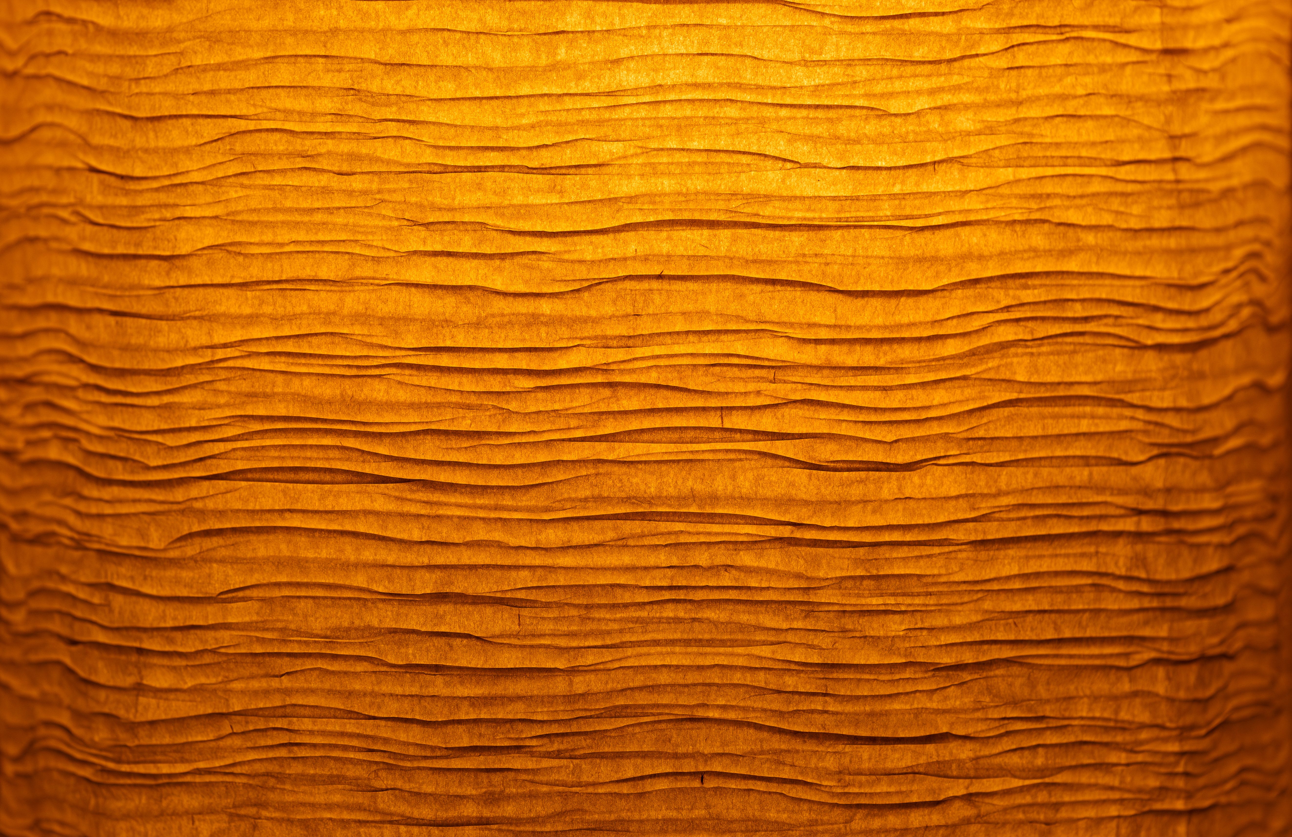 Close-up of crinkled orange paper texture, reminiscent of a warm glowing light.