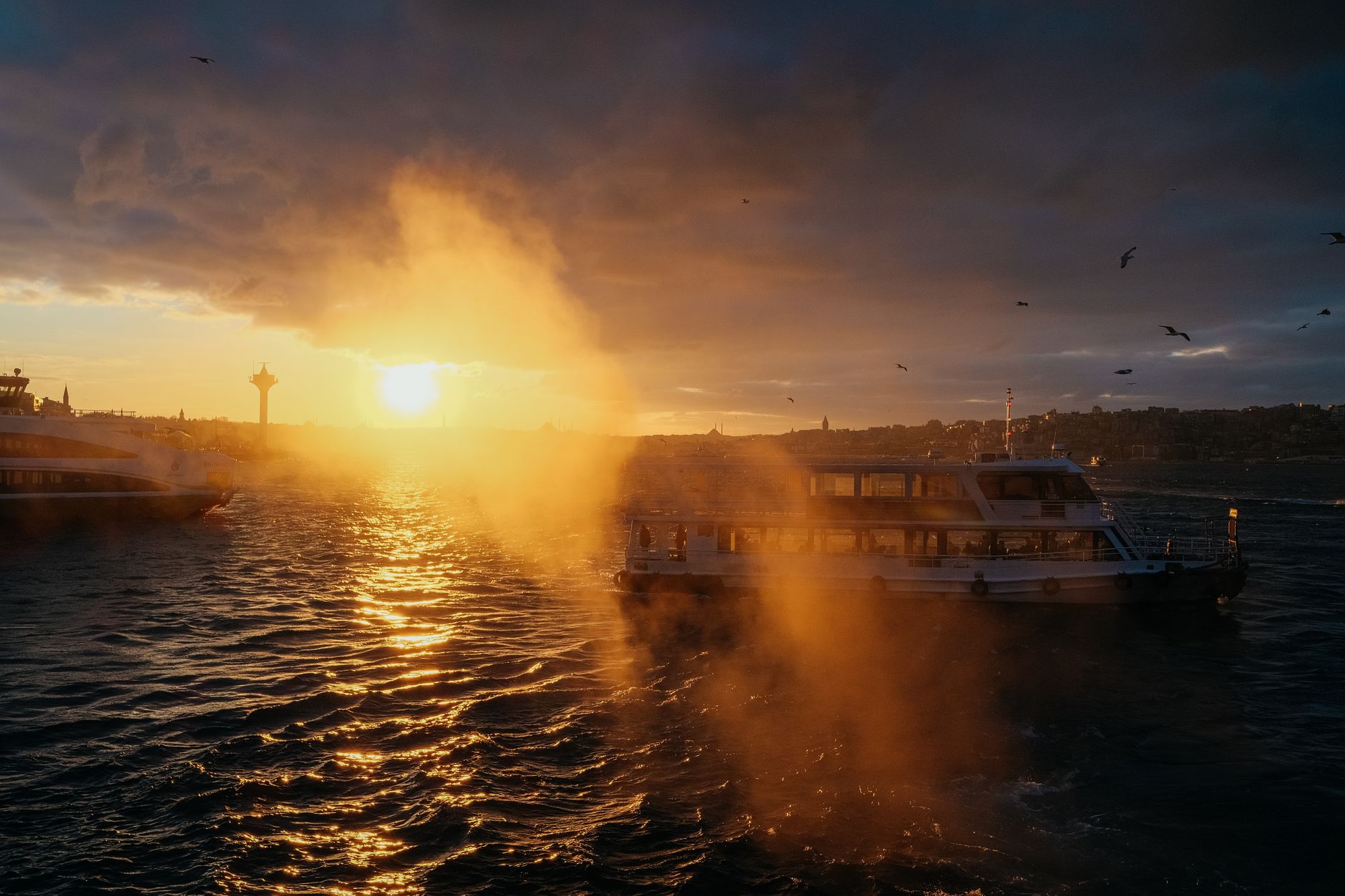 Golden sunset over Bosphorus Strait with ferries and seagulls in view.
