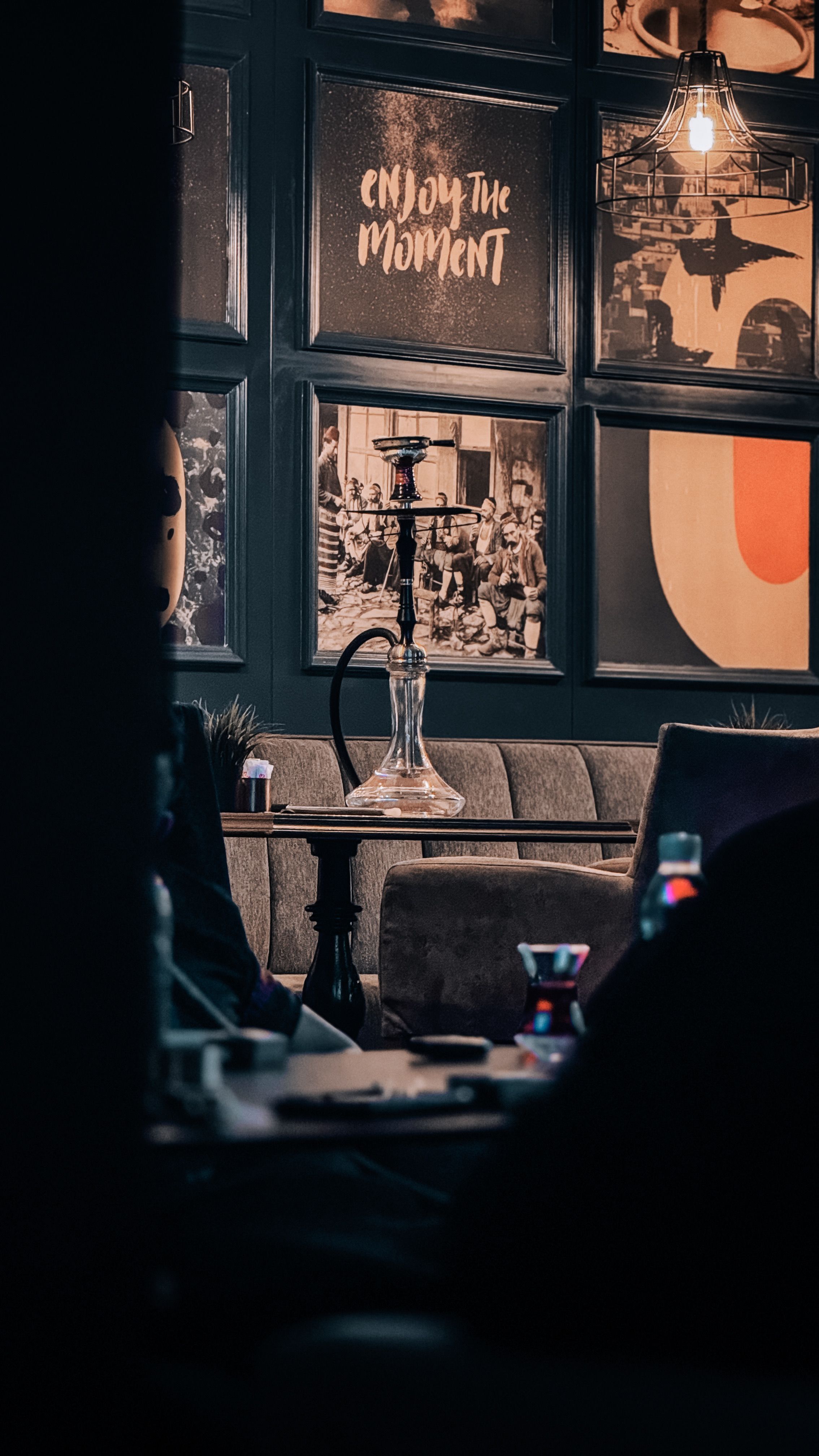 Warm lounge interior featuring a hookah on a table with artistic wall decor.