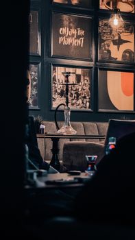 Warm lounge interior featuring a hookah on a table with artistic wall decor.