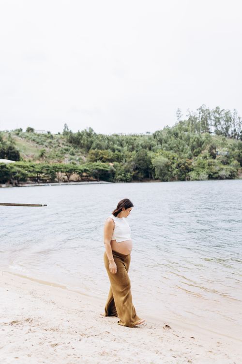 Free Expectant mother enjoying a peaceful stroll by a scenic lakeside with lush greenery. Stock Photo