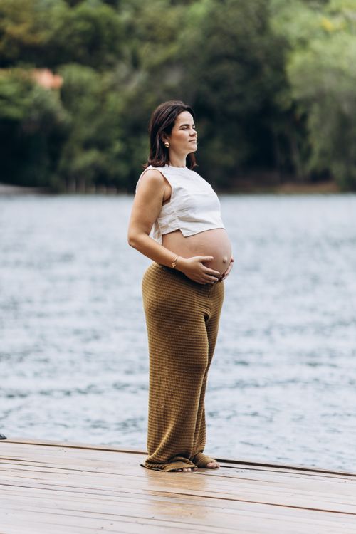 Free Pregnant woman in peaceful outdoor setting by a lake, embracing nature. Stock Photo