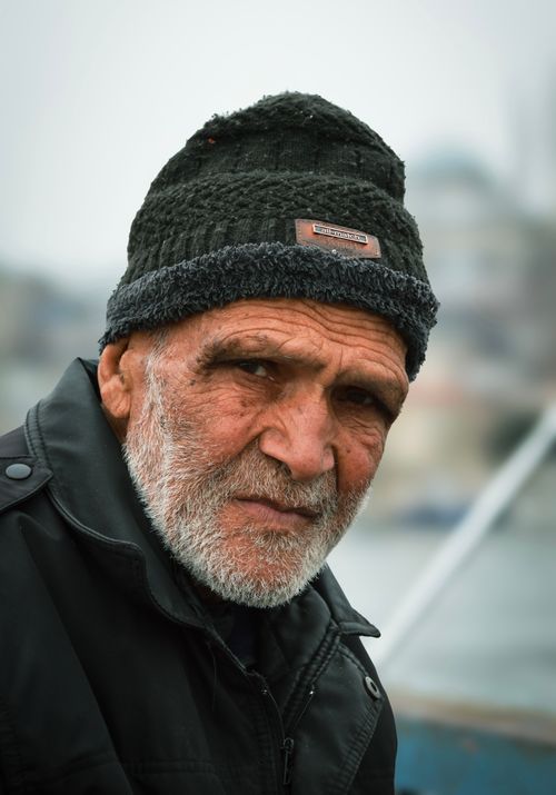 Free Portrait of an elderly man wearing a beanie in Istanbul with a blurred cityscape background. Stock Photo