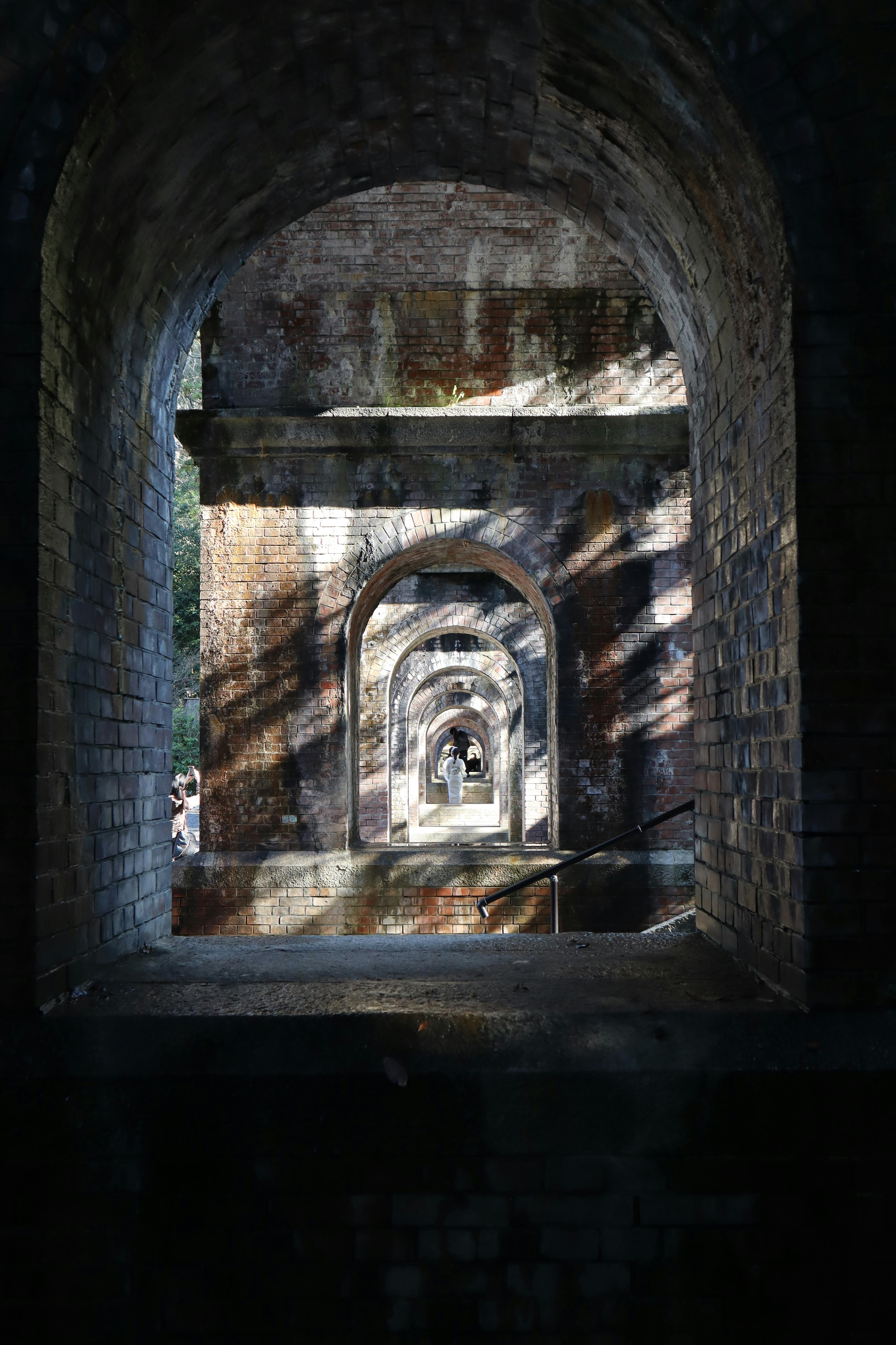 View through ancient brick arches of a historic aqueduct in Kyoto, Japan.