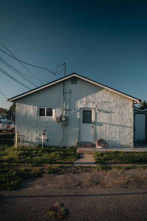 Free Small white suburban house with sunny exterior and vibrant blue sky. Stock Photo