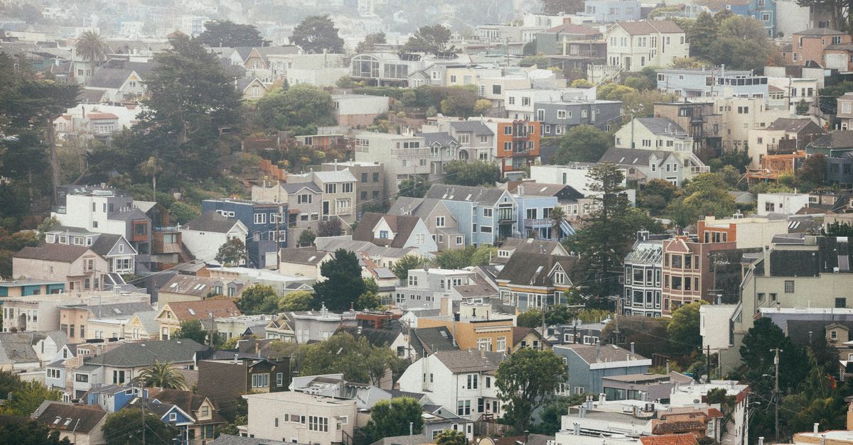 Scenic view of the foggy San Francisco hills with colorful houses under a cloudy sky.