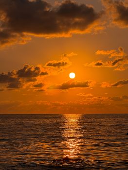 A breathtaking sunset with vibrant orange hues reflecting on calm ocean waves.