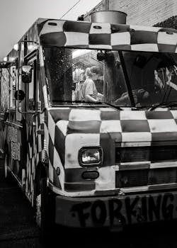 Monochrome image of a food truck at night with a person inside.