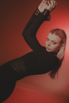 Creative portrait of a woman in black dress with red dramatic lighting.