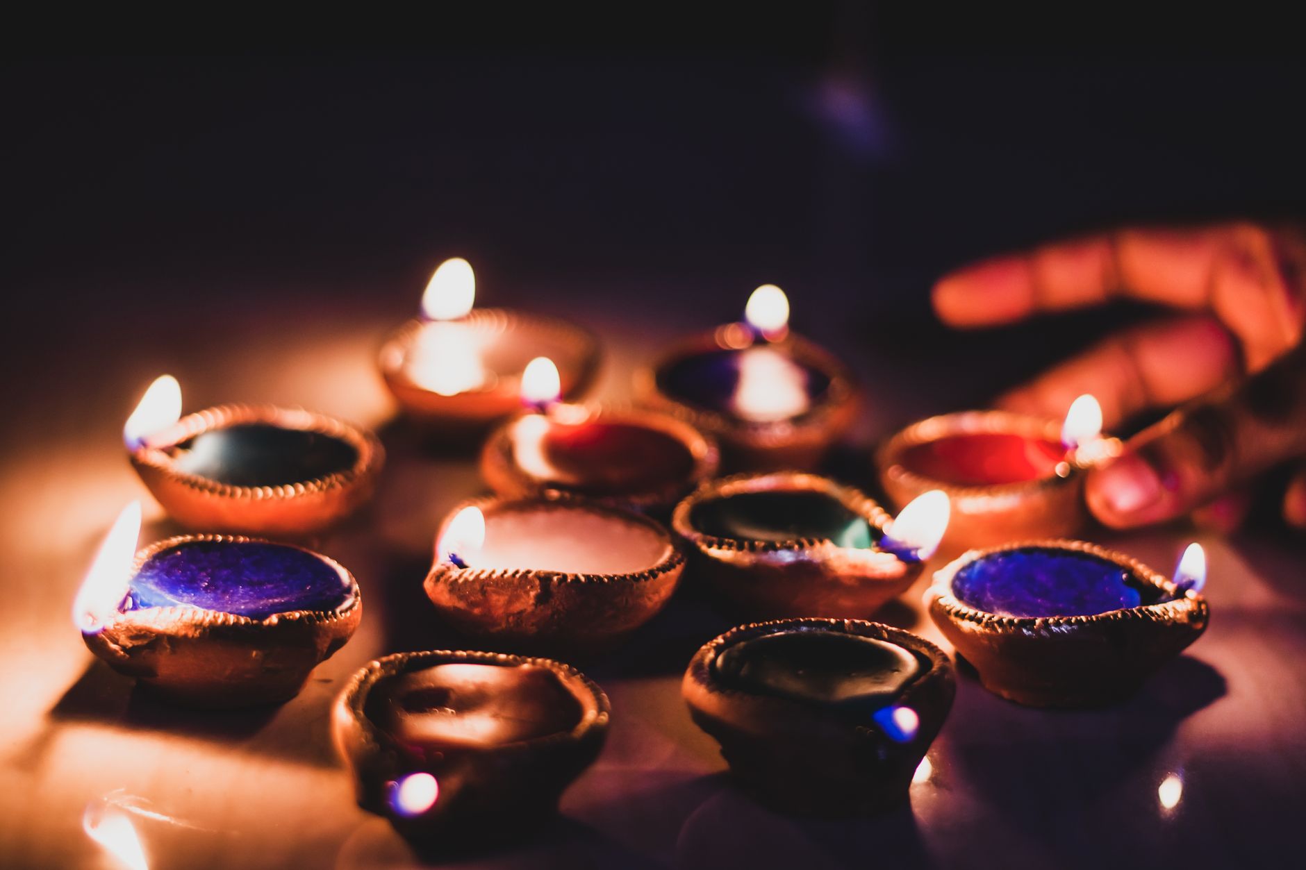 रंगीन दिवाली दीयों के बीच तीन पत्ती के पत्ते और व्यवस्थित चिप्स लकड़ी की मेज पर रखे हुए