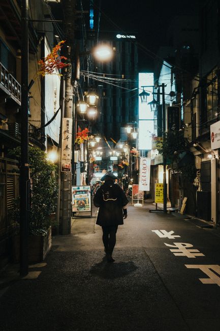 Person walking in a neon-lit city alley at night, urban exploration.