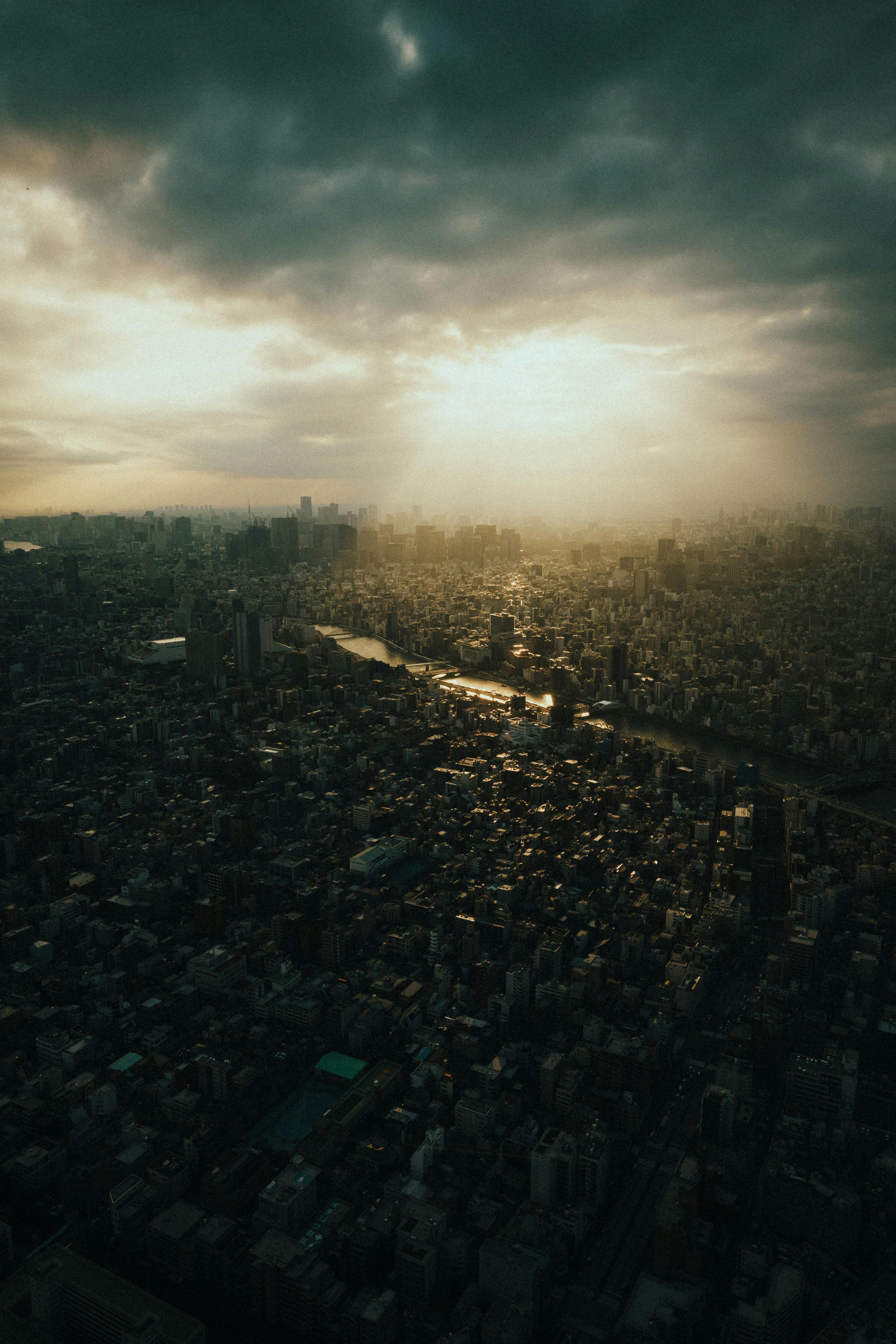 A dramatic aerial view of Tokyo cityscape with sunset clouds casting shadows over the skyline.