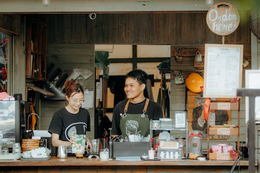 Two baristas at a cozy coffee shop counter, ready to serve customers.