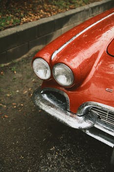 A detailed view of a classic red car's headlight and front design, showcasing vintage automotive style.