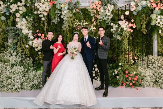 Bride and groom with friends at a colorful wedding ceremony with lush floral arrangements.