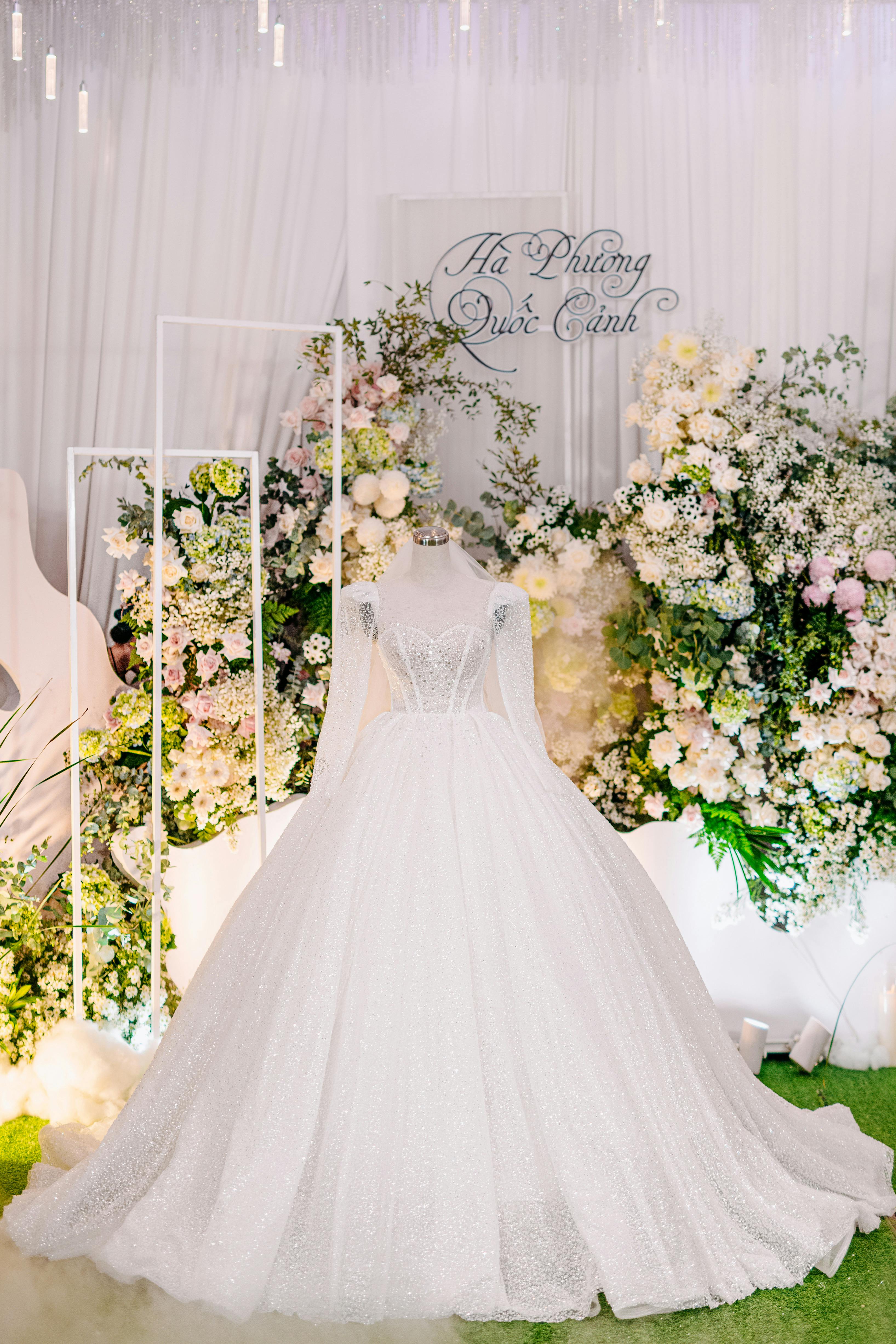 Stunning wedding dress showcased with lush floral backdrop in a serene indoor setting.