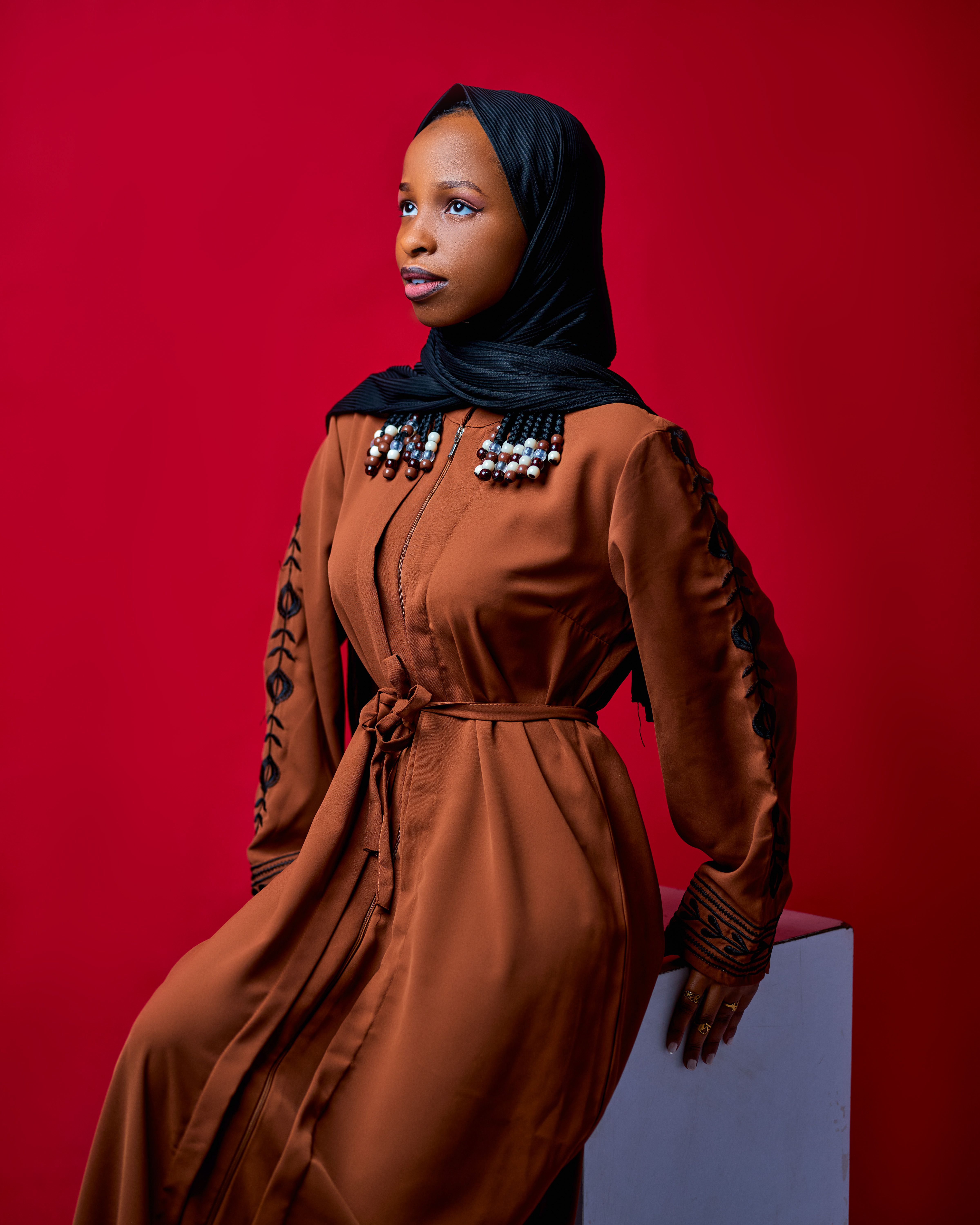 Striking portrait of a woman in a traditional dress against a red background.