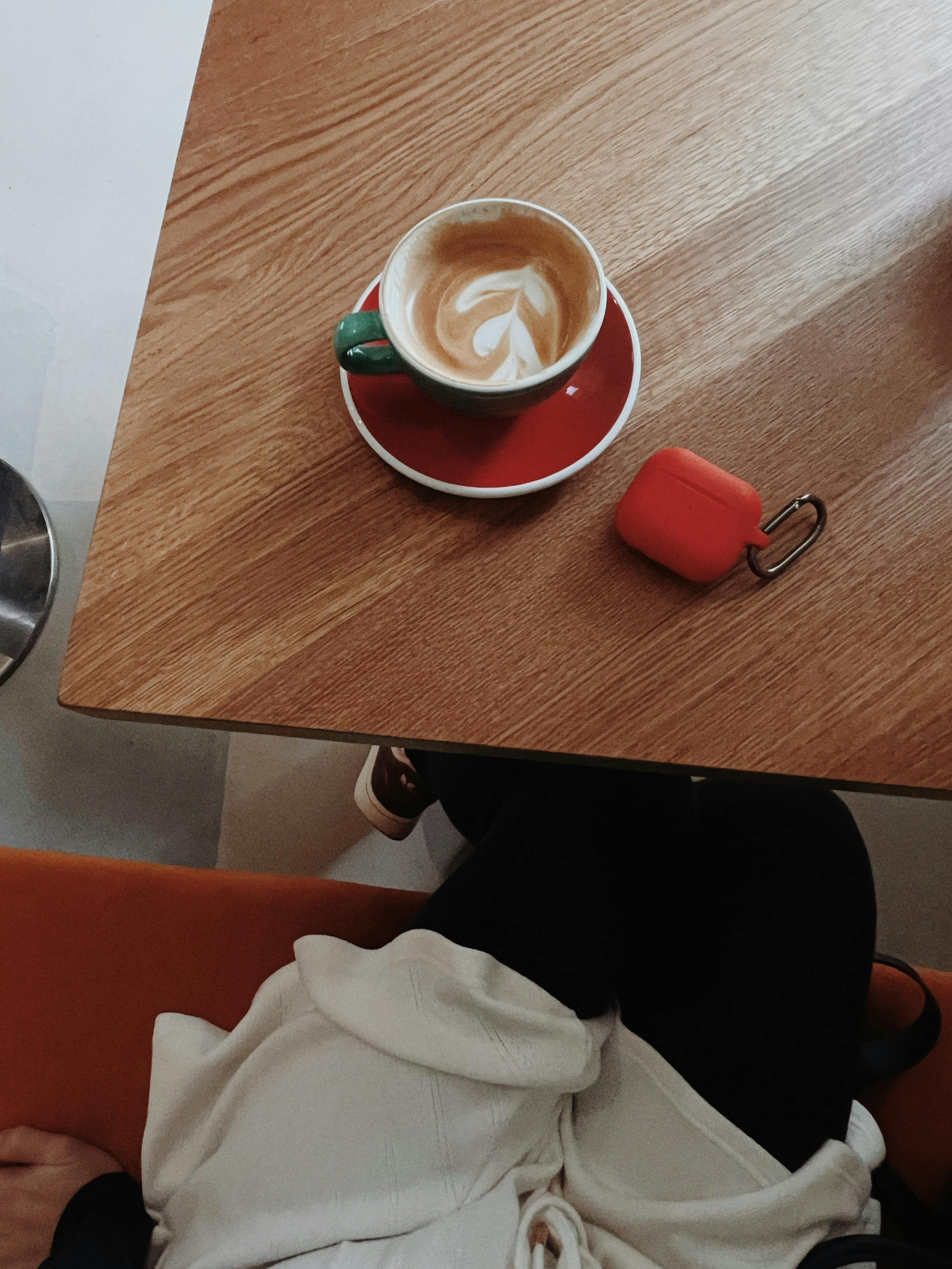 bezplatná Útulné prostředí kavárny s latte a sluchátky na dřevěném stole, zachycené shora. Základová fotografie