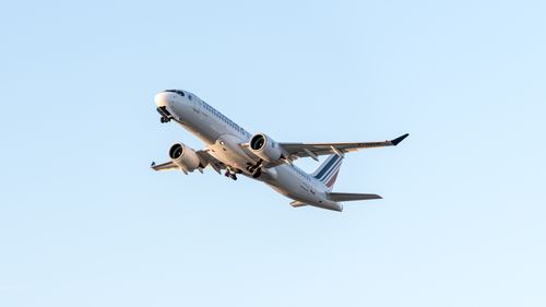 Free Jet aircraft flying high against a clear sky, showcasing air travel and aviation. Stock Photo