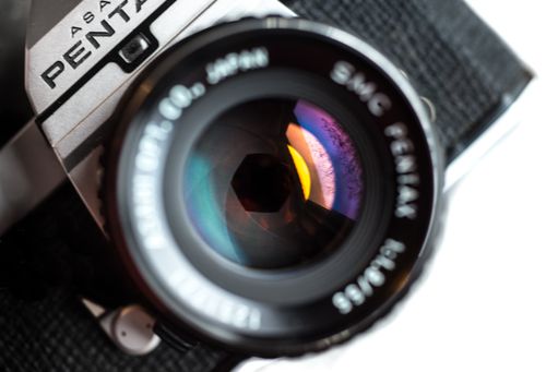 Free Detailed close-up of a classic Pentax camera lens showing colorful reflections. Stock Photo