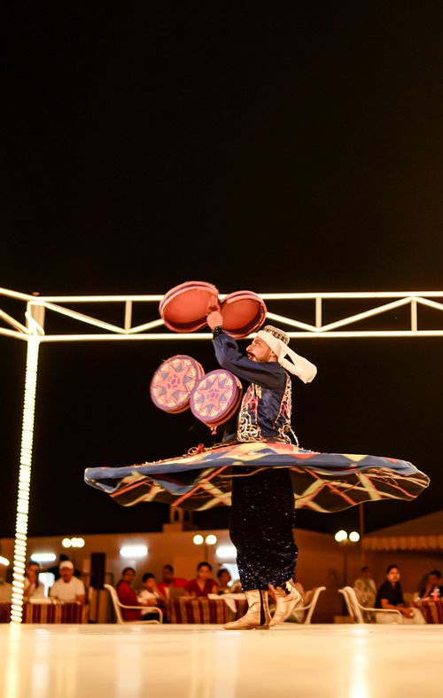 Free A mesmerizing Tanoura dancer spinning under night lights in a cultural setting. Stock Photo