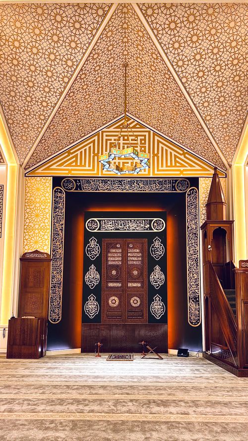 Free Beautifully decorated mosque prayer hall with ornate Islamic patterns and wooden elements. Stock Photo