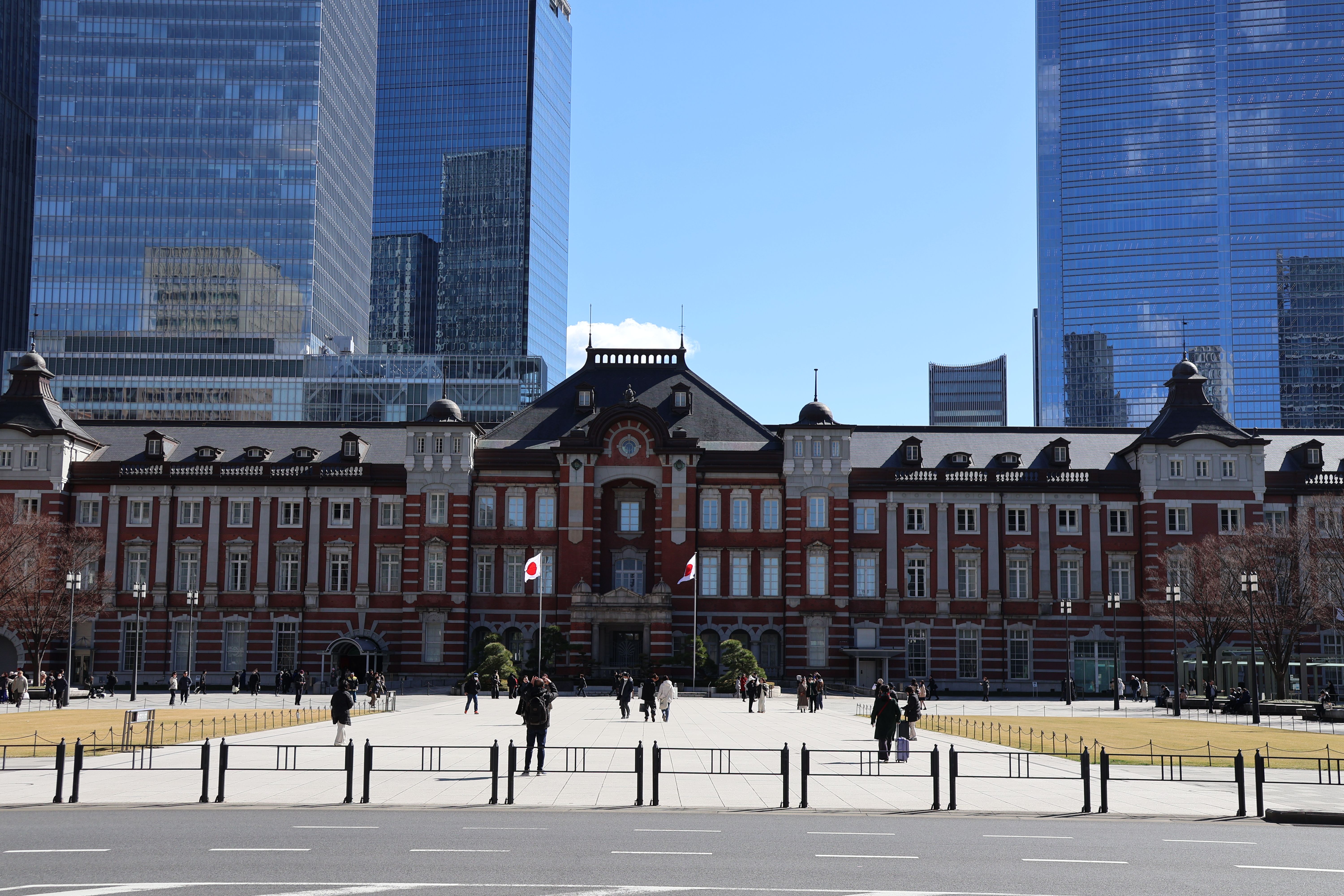 Tokyo Station's historic facade with skyscrapers in the background on a clear day.