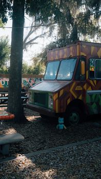 Vibrant food truck parked in a serene outdoor setting with trees and picnic tables.
