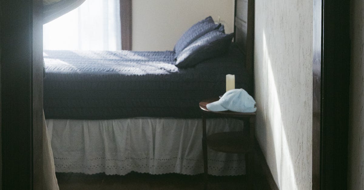 Peaceful sunlit bedroom interior with wooden floor and soft drapes, perfect for relaxation.