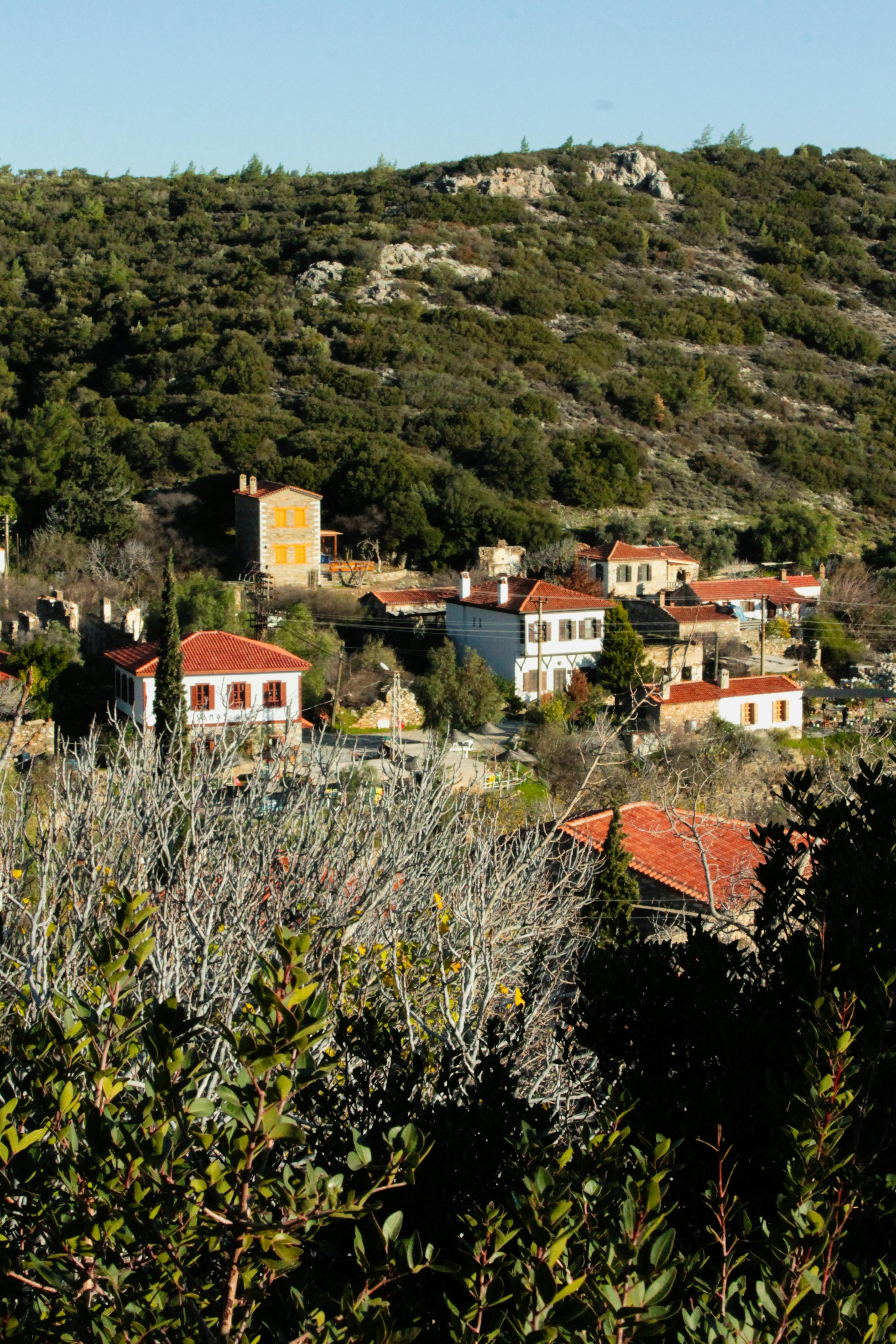 Picturesque village with red rooftops nestled in lush hillside, showcasing Mediterranean architecture.