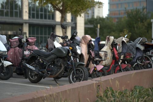 Free A row of parked scooters and motorcycles in an urban outdoor setting with protective covers. Stock Photo