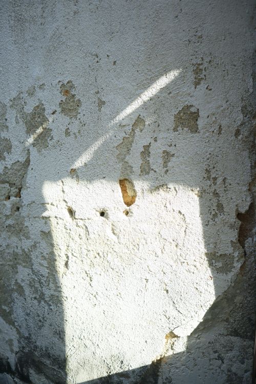 Free A textured white wall displaying an artistic pattern of light and shadow. Stock Photo