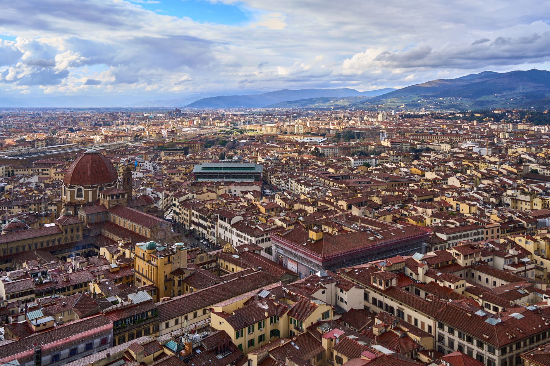 Stunning aerial panorama of Florence, Italy showcasing historic architecture against a mountainous backdrop.