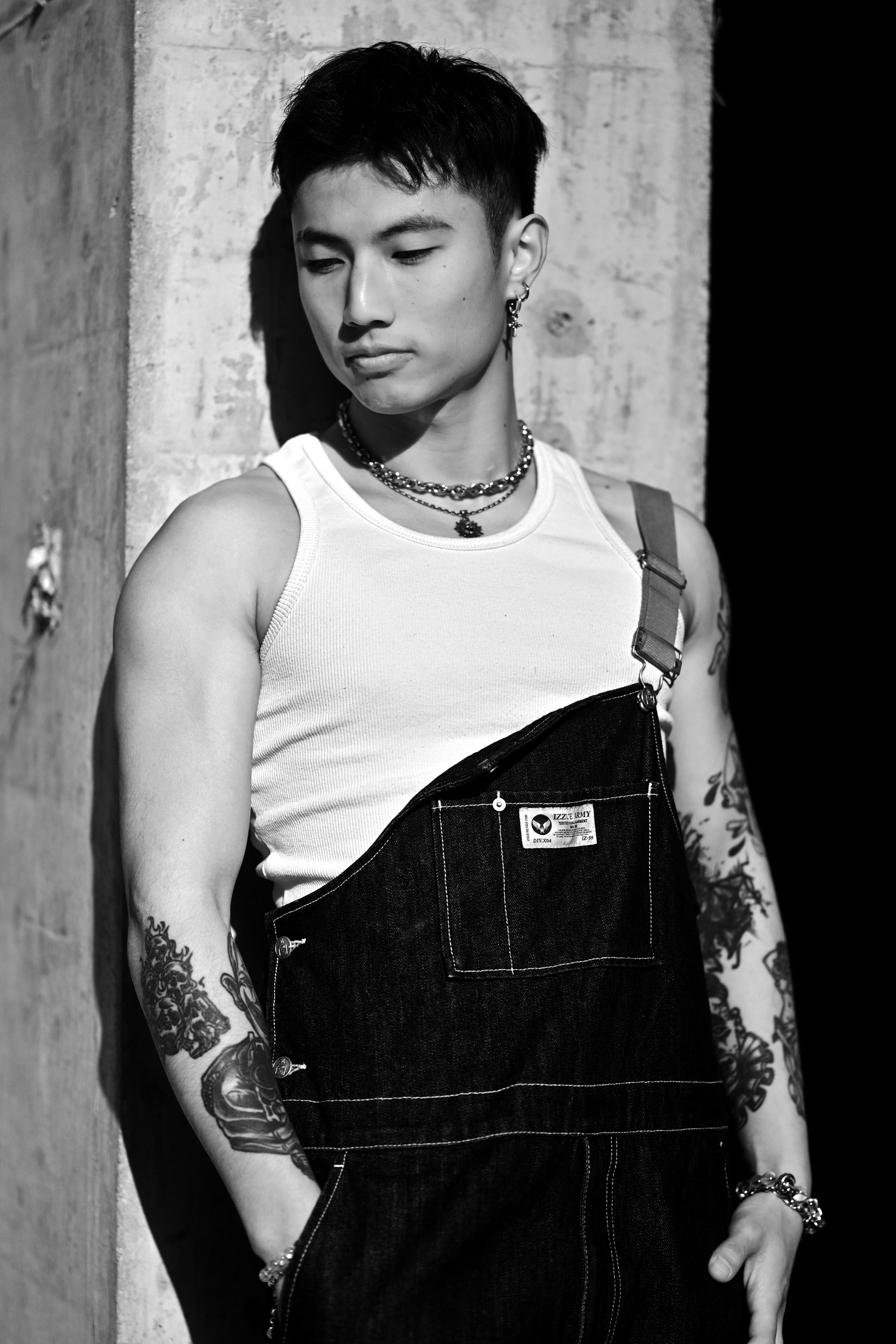Stylish black and white portrait of a tattooed man in urban setting.