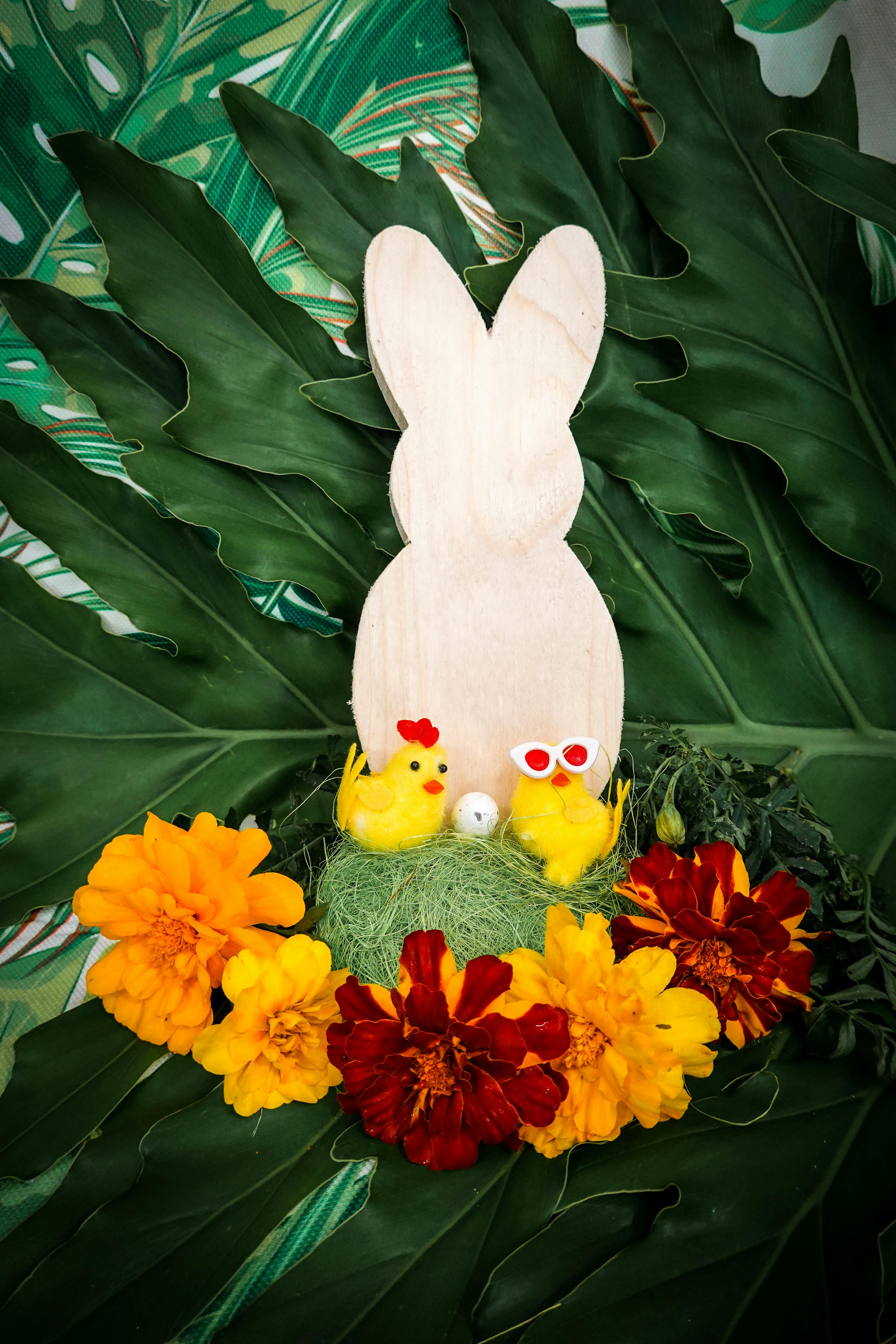 Festive Easter display featuring a wooden bunny and cheerful chicks surrounded by vibrant flowers.
