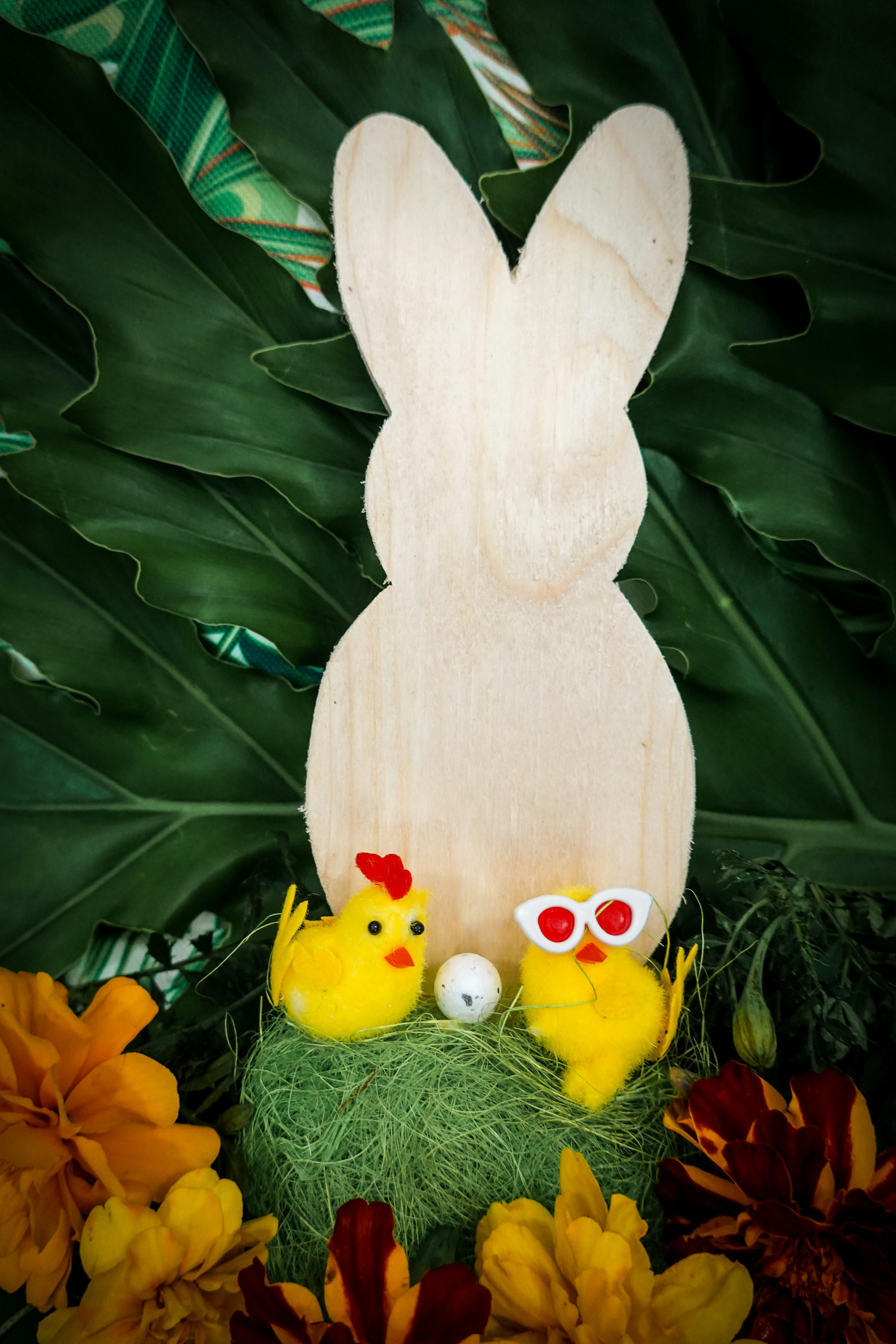 Festive Easter scene with wooden bunny, yellow chicks, flowers, and greenery.