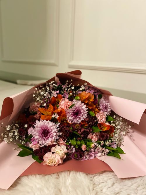 Free Colorful bouquet with pink chrysanthemums and orange flowers, elegantly wrapped in pink paper. Stock Photo