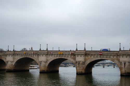Free A scenic view of the historical Pont Neuf bridge over the Seine River in Paris on a cloudy day. Stock Photo