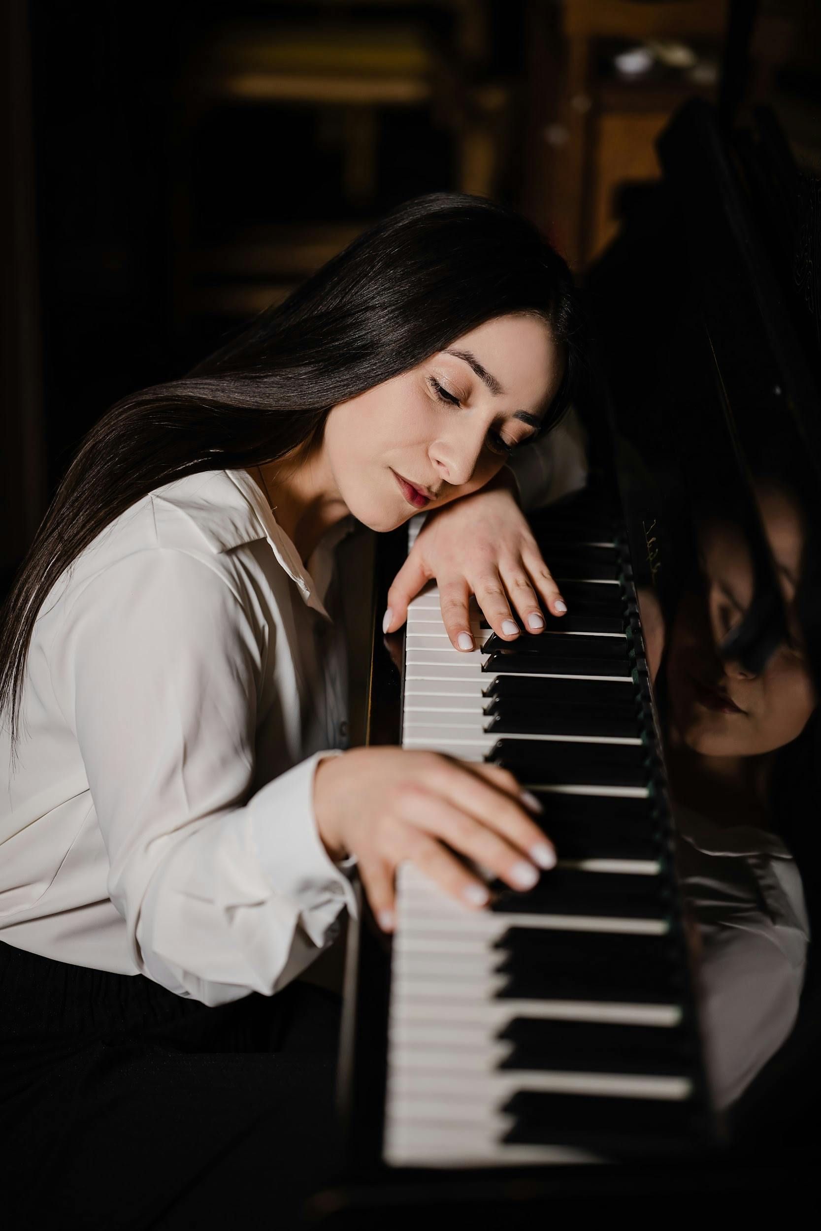 A peaceful woman rests on a grand piano, reflecting tranquility and connection to music.