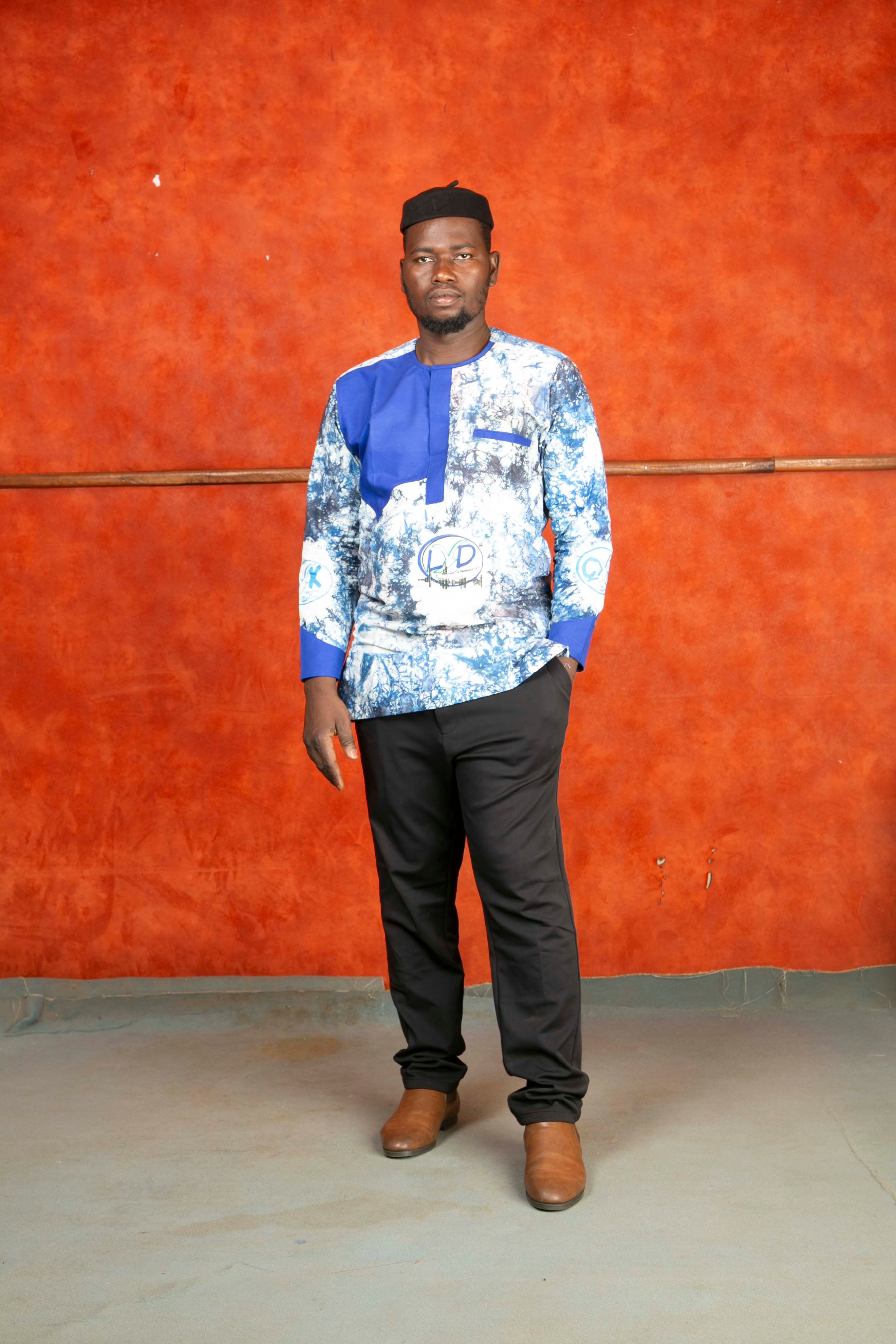 Portrait of a man in traditional African attire against a warm orange background.