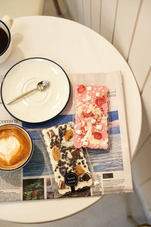 Free Delicious handmade chocolate bars with a cappuccino on a cozy cafe table setting. Stock Photo