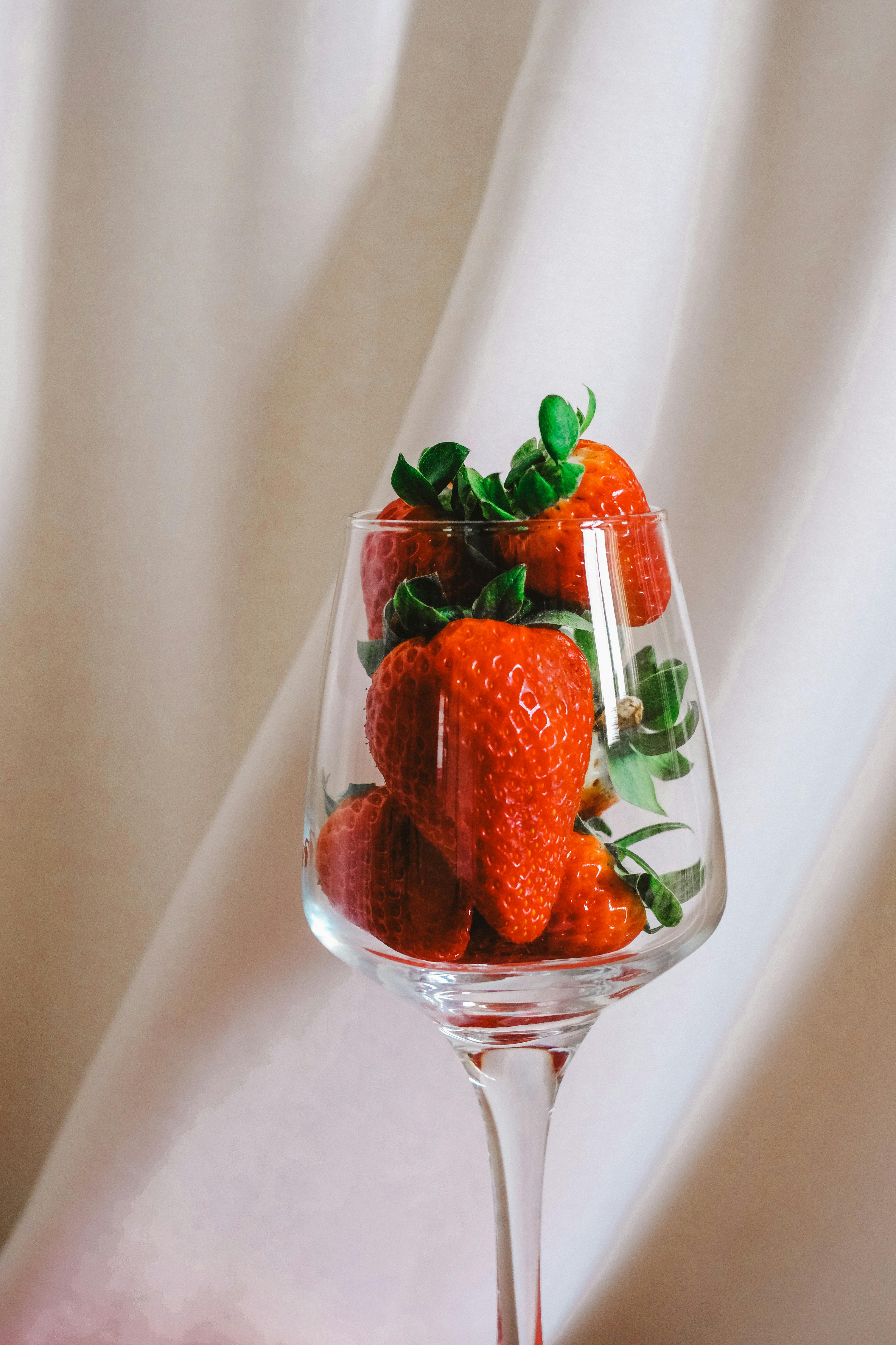 Close-up of ripe strawberries in a wine glass with a soft background, elegant and fresh.