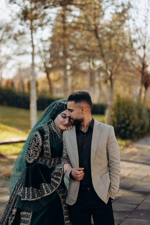 Free A loving couple embraces in traditional attire in a serene outdoor setting. Stock Photo