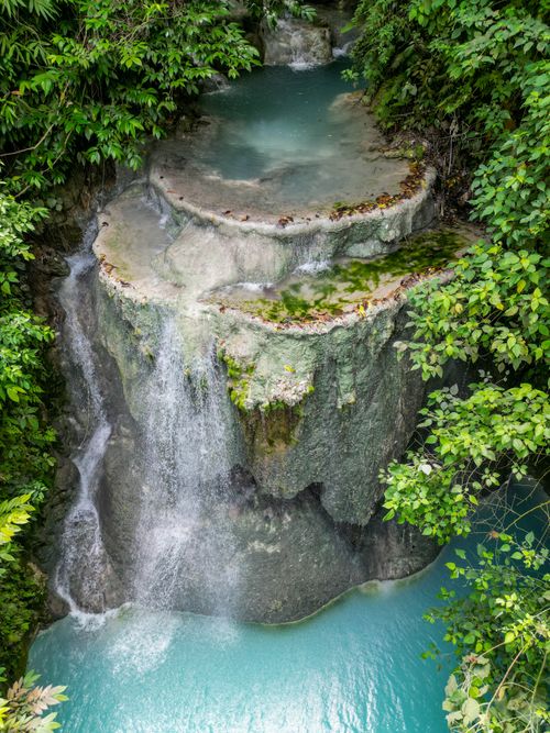 Free A breathtaking aerial shot of a lush waterfall in the Philippines surrounded by greenery. Stock Photo