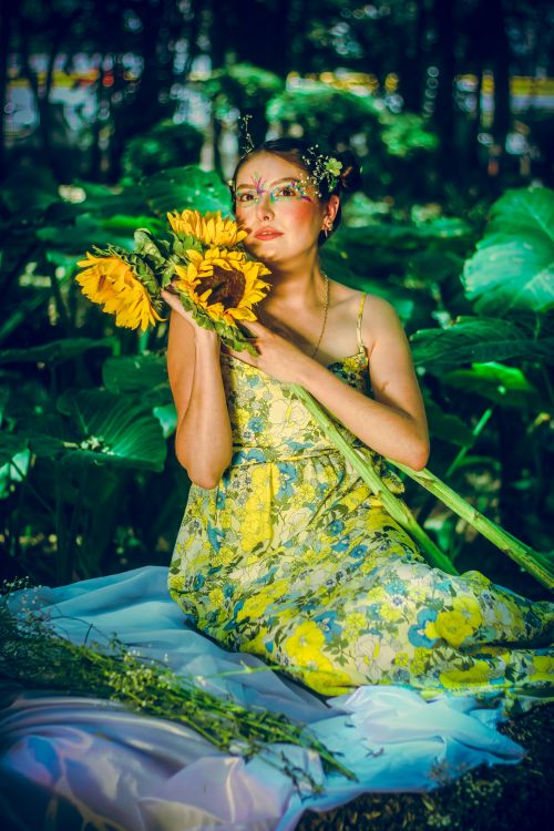 Free A vibrant outdoor portrait of a woman in colorful attire with sunflowers, conveying a sense of creative beauty. Stock Photo