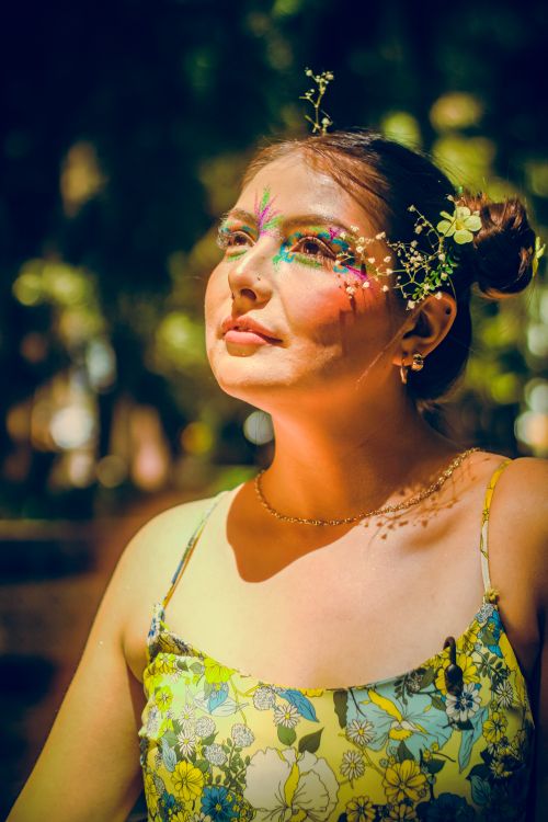 Free Vibrant artistic makeup and floral adornments in an outdoor park setting. Captivating and colorful portrait. Stock Photo