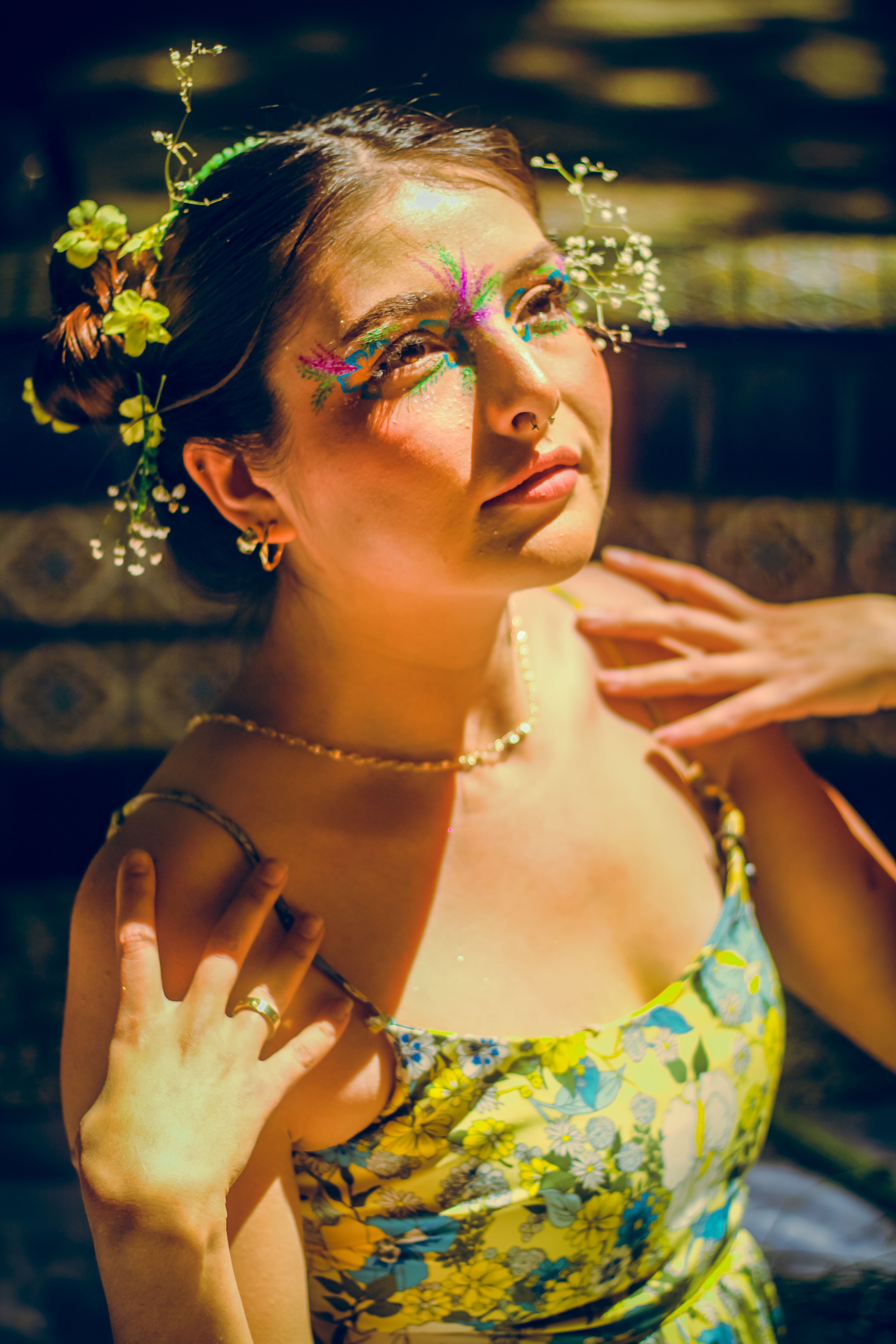 Portrait of a woman with floral makeup and accessories outdoors in bright sunlight.
