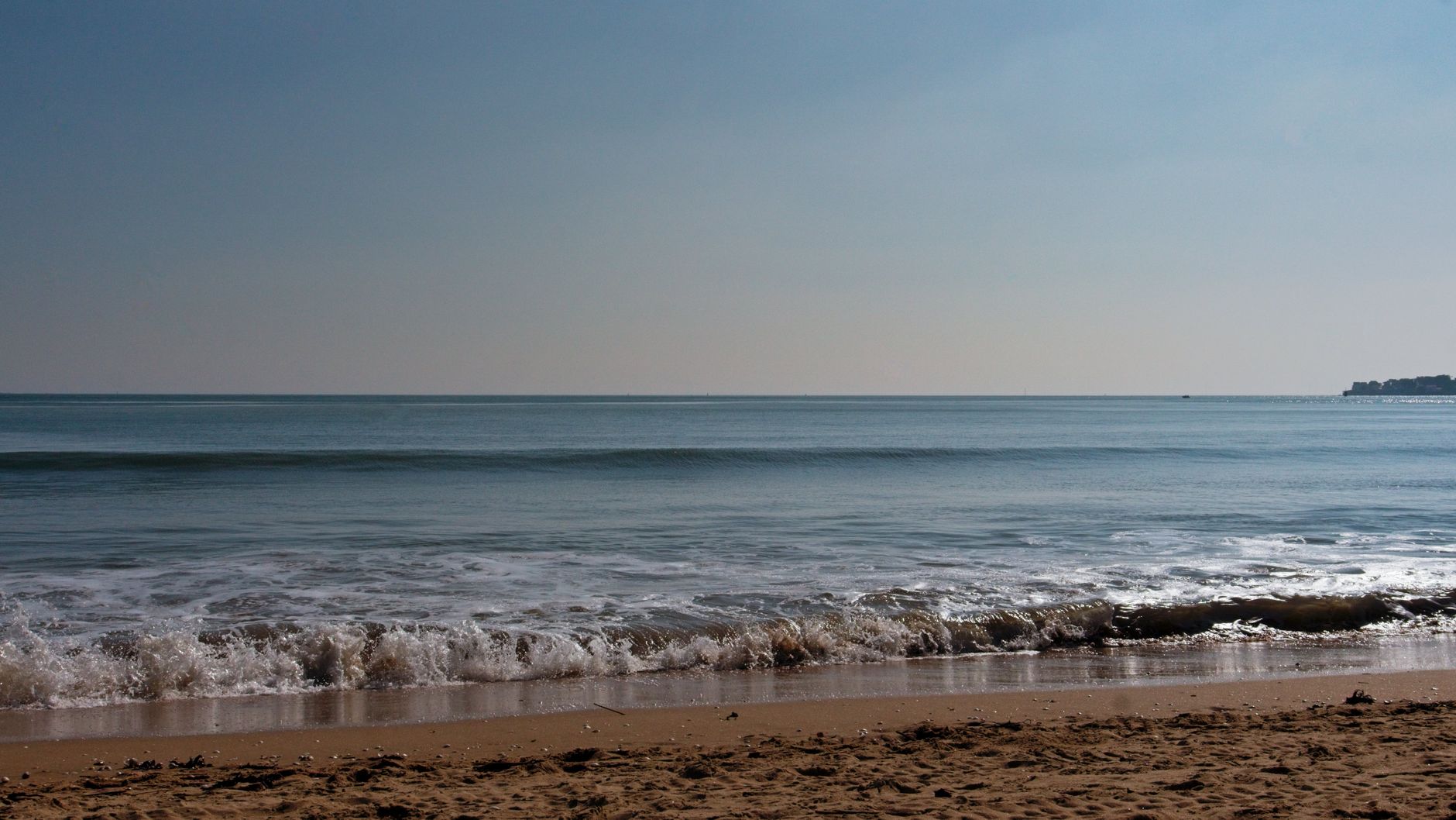 Escena tranquila de la playa en La Baule con suaves olas y un cielo azul claro.