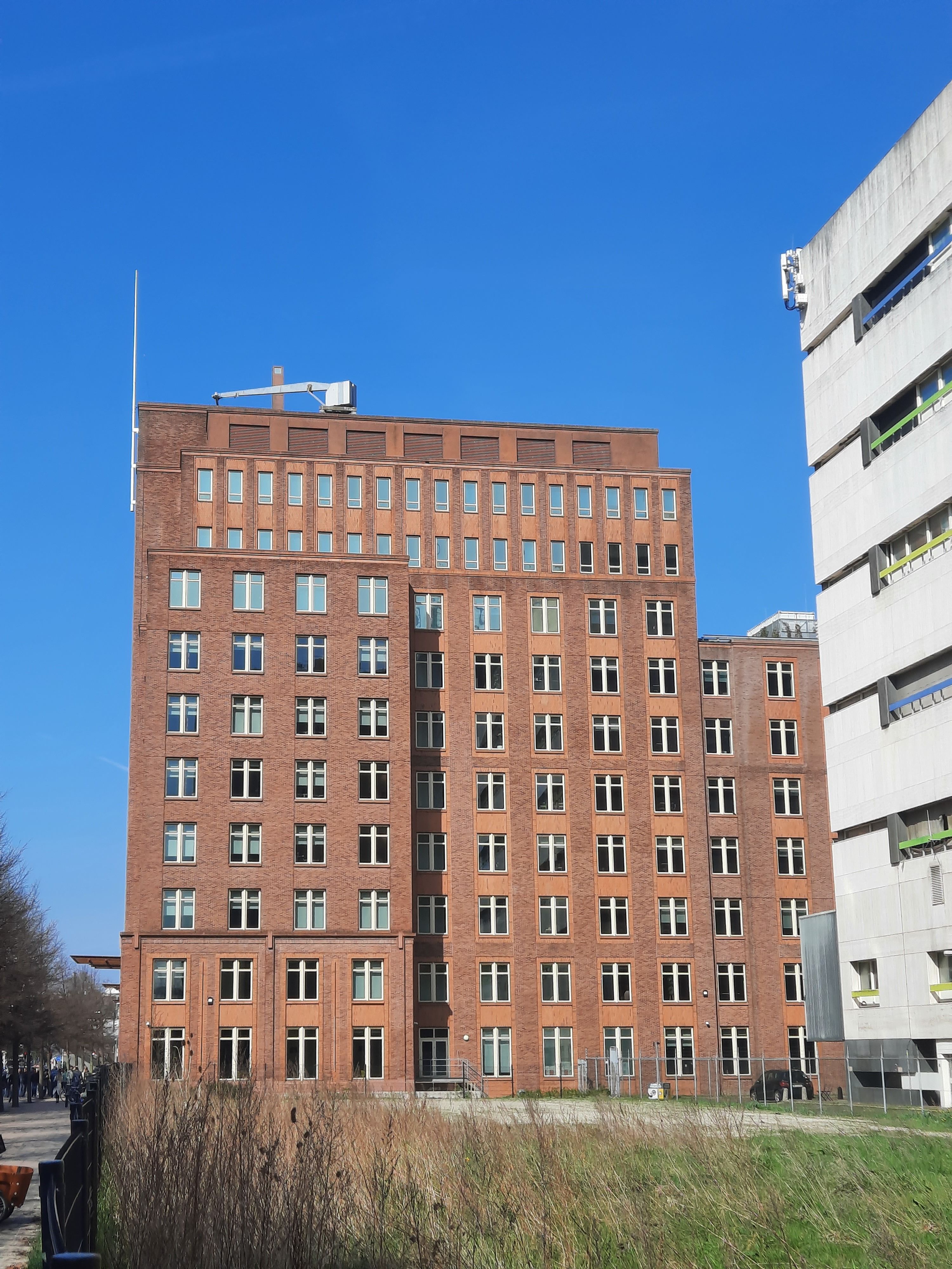 Een klassiek rood bakstenen gebouw in Den Haag tegen een strakblauwe lucht, een toonbeeld van stedelijke architectuur.