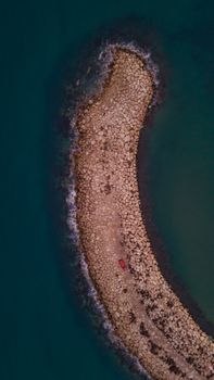 Aerial view of a curved rocky jetty extending into the sea in Kumköy, Antalya, Türkiye.